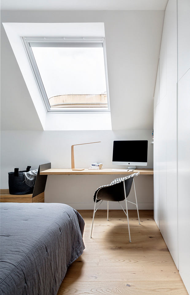 Minimalist bedroom with skylight, desk and computer setup.