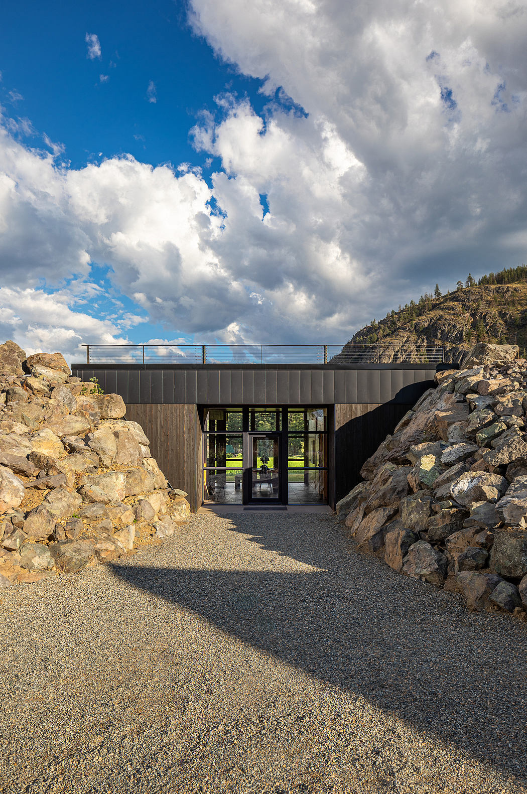 An architectural masterpiece nestled amidst rugged terrain, featuring a striking glass entryway and sleek, modern design.
