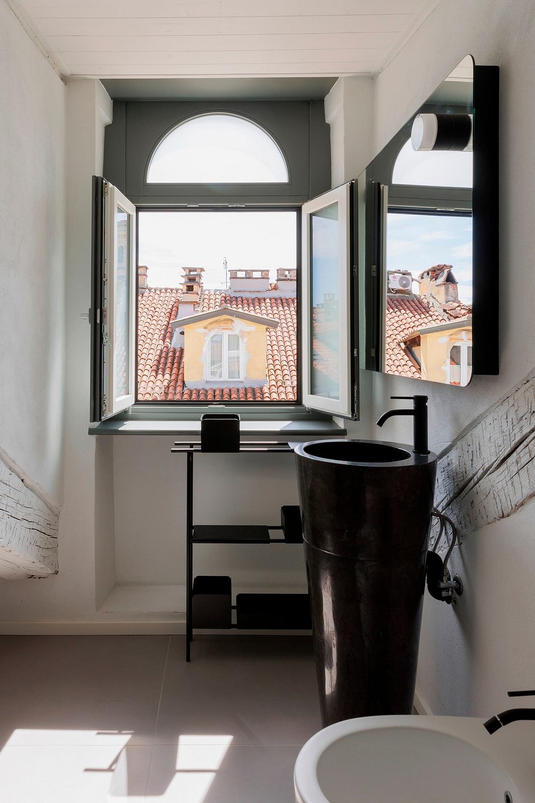 A modern bathroom with an arched window overlooking a city skyline, featuring sleek black fixtures.