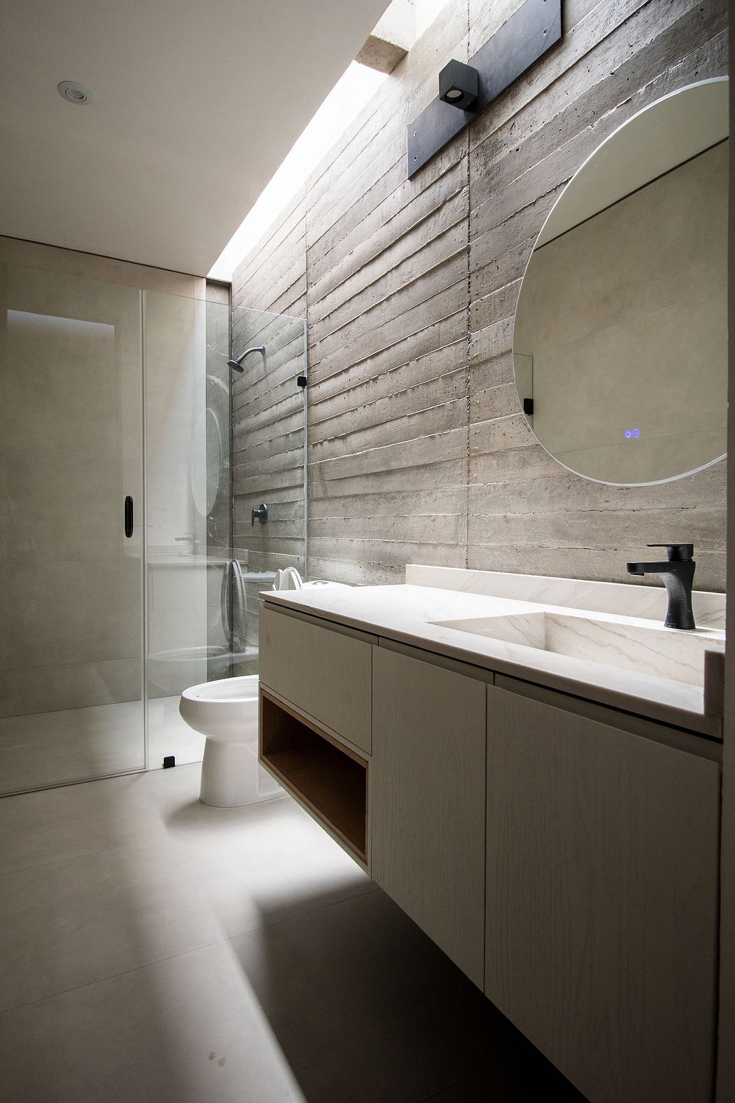 Modern bathroom with wooden accents, floating vanity, circular mirror, and walk-in shower