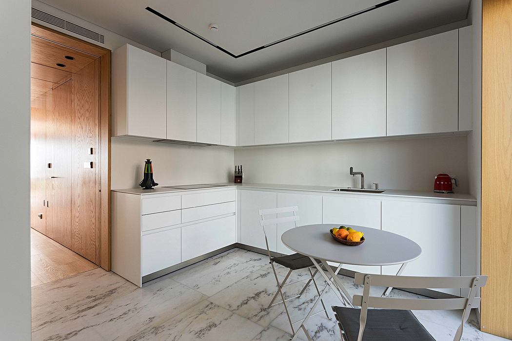 Modern kitchen with white cabinets, marble floor, and a small dining table.