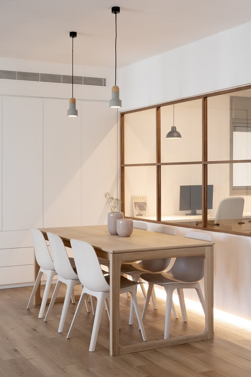 Contemporary dining area with wooden table, white chairs, and glass partition.