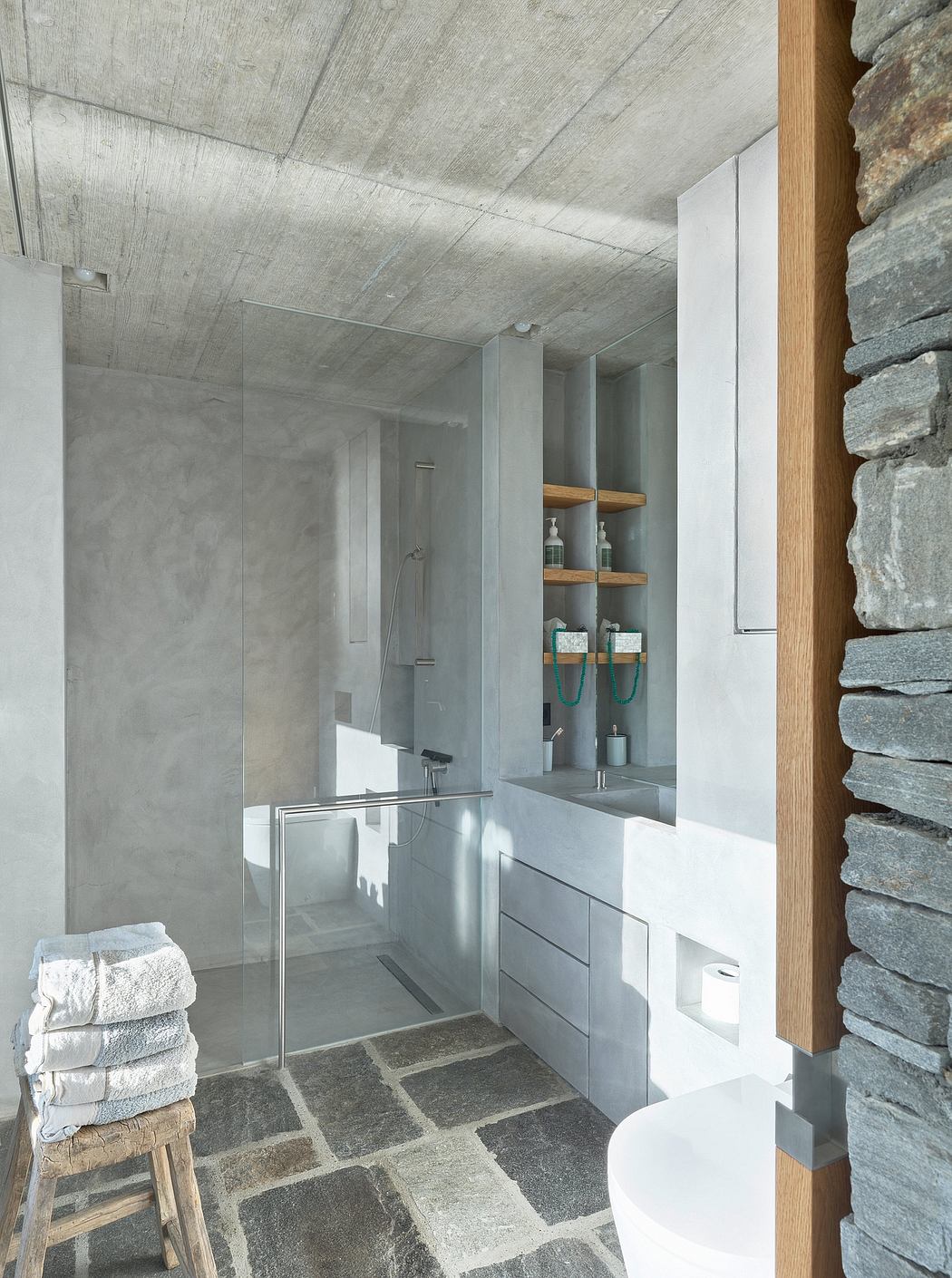 Minimalist bathroom with concrete finish and stone wall accents.