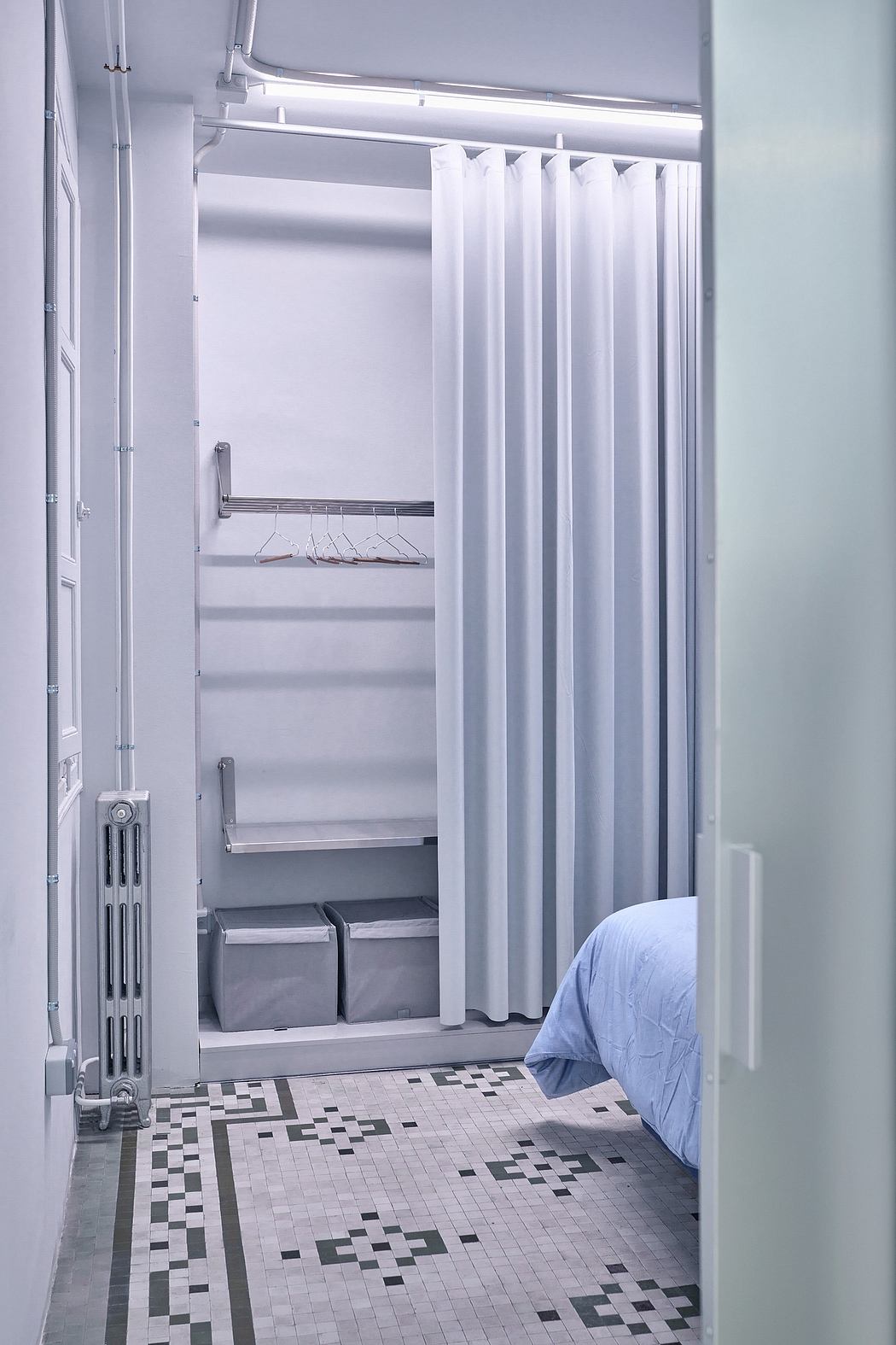 A minimalist, white-toned bedroom with a built-in closet and tile flooring.