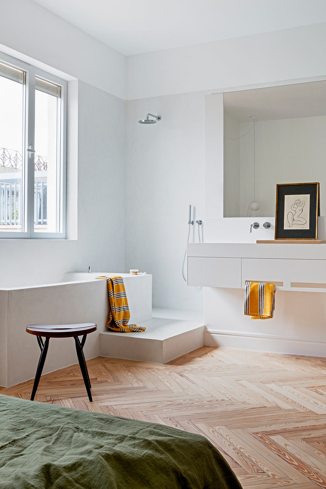 Modern bedroom with an open en suite bathroom, herringbone floor, and minimal