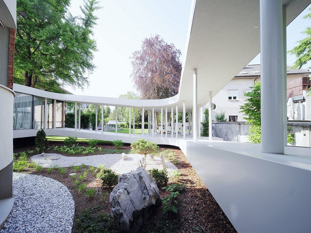 A modern glass-enclosed patio with a lush green courtyard and a rock feature.