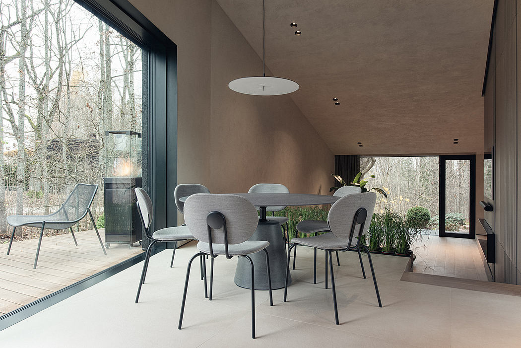 Sleek, modern dining space with floor-to-ceiling windows offering scenic woodland views.