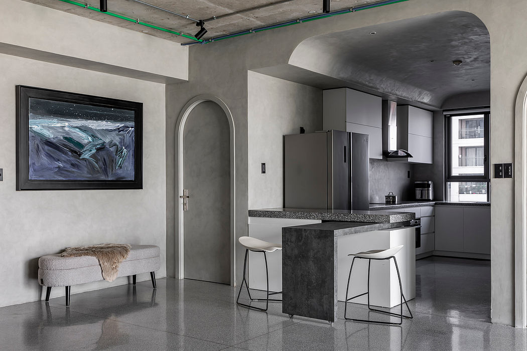 Sleek, modern kitchen with concrete walls, brushed metal appliances, and an arched entryway.