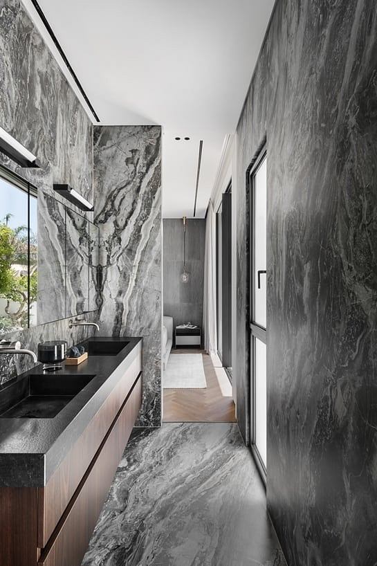 Sleek, minimalist bathroom with striking marble walls and fixtures in muted tones.