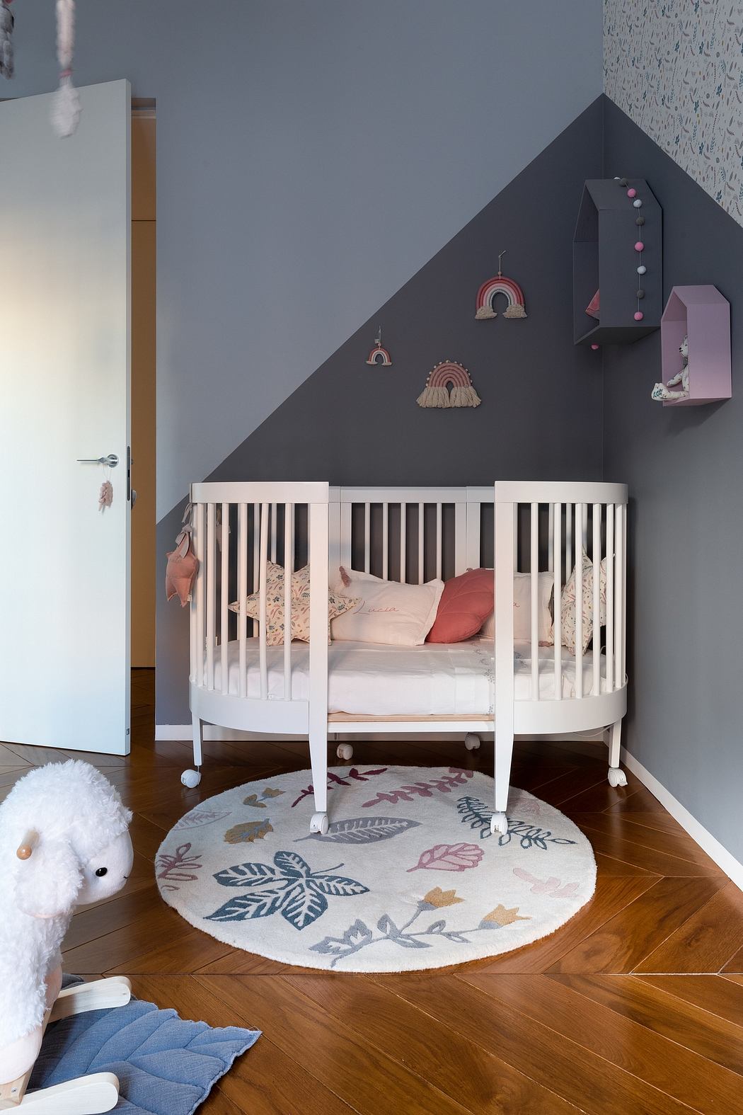 A cozy nursery room with a white crib, decorative rug, and gray walls with