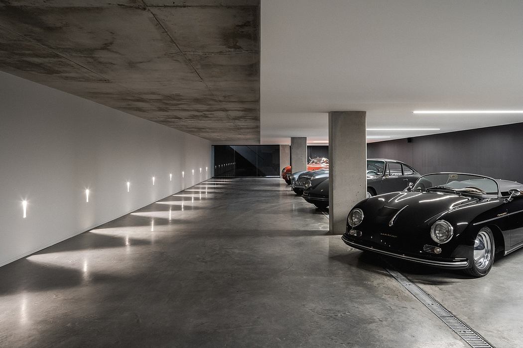 A modernist garage with sleek concrete architecture and vintage sports cars.