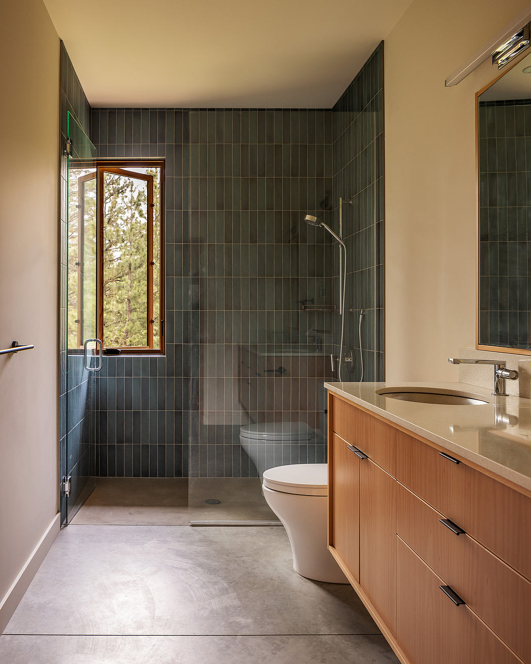 Modern bathroom with a walk-in shower, wooden vanity, and a window with a