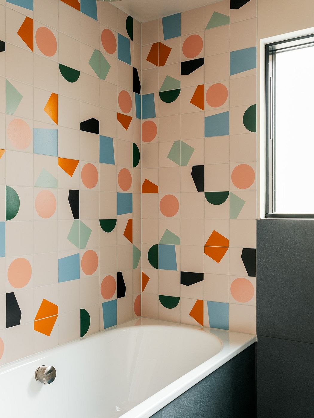 Contemporary bathroom with colorful geometric tiled walls.