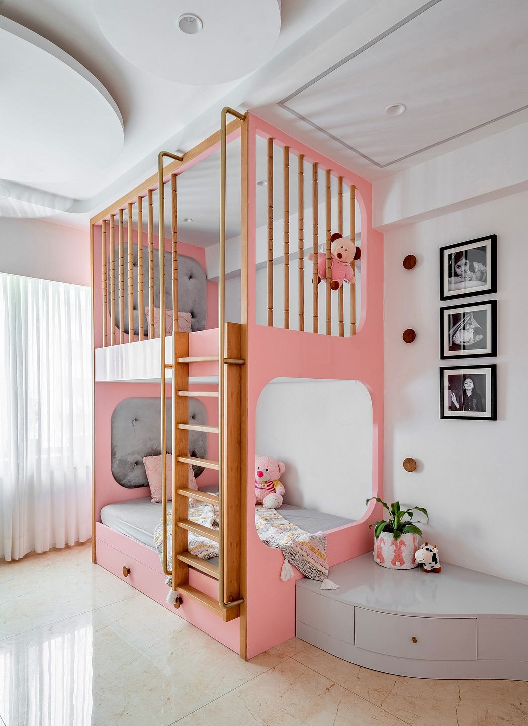 Pink children's room with bunk beds, photos on wall, and plush toys.