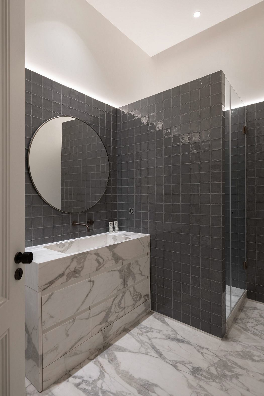 Elegant bathroom with marble sink, gray tiles, and a glass shower.