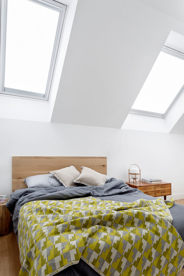Modern attic bedroom with skylights and minimalist decor.