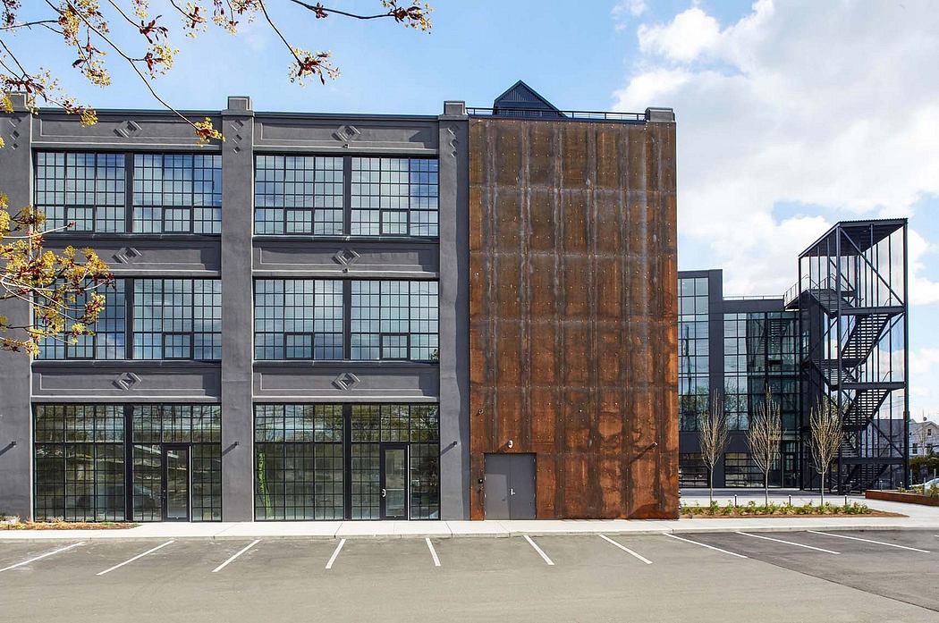 A modern industrial-style building with large windows, steel beams, and a rusted metal wall.