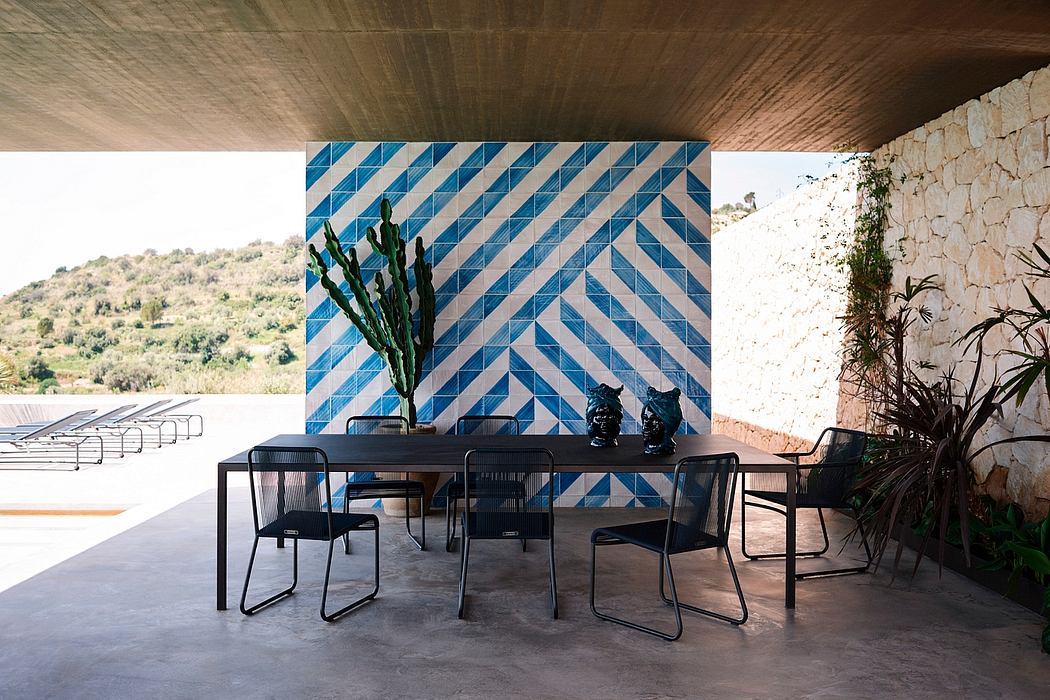 Contemporary outdoor dining area with geometric blue wall design and minimalist furniture.