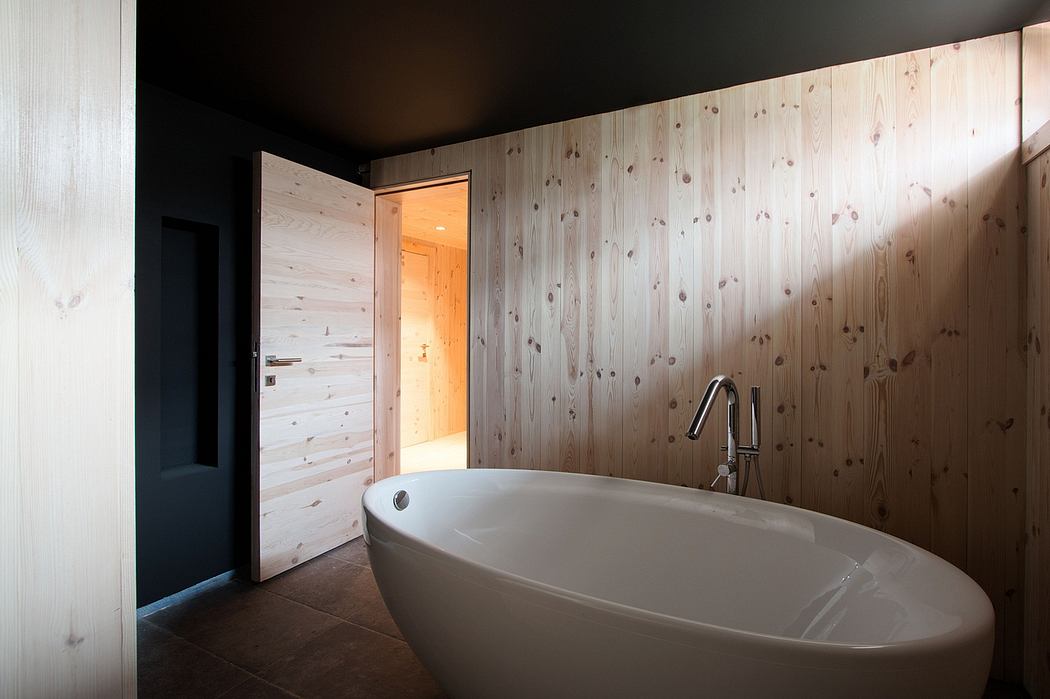 Rustic bathroom with large freestanding tub, wooden paneled walls, and recessed lighting.