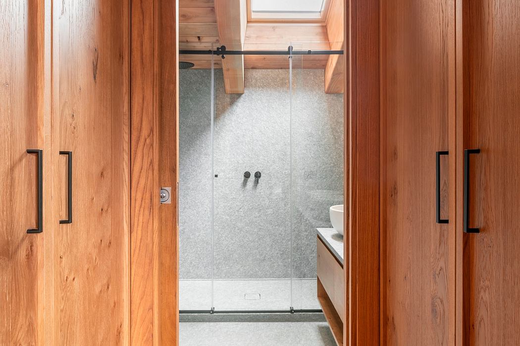 Modern bathroom with clean wood paneling, glass shower, and minimalist design.