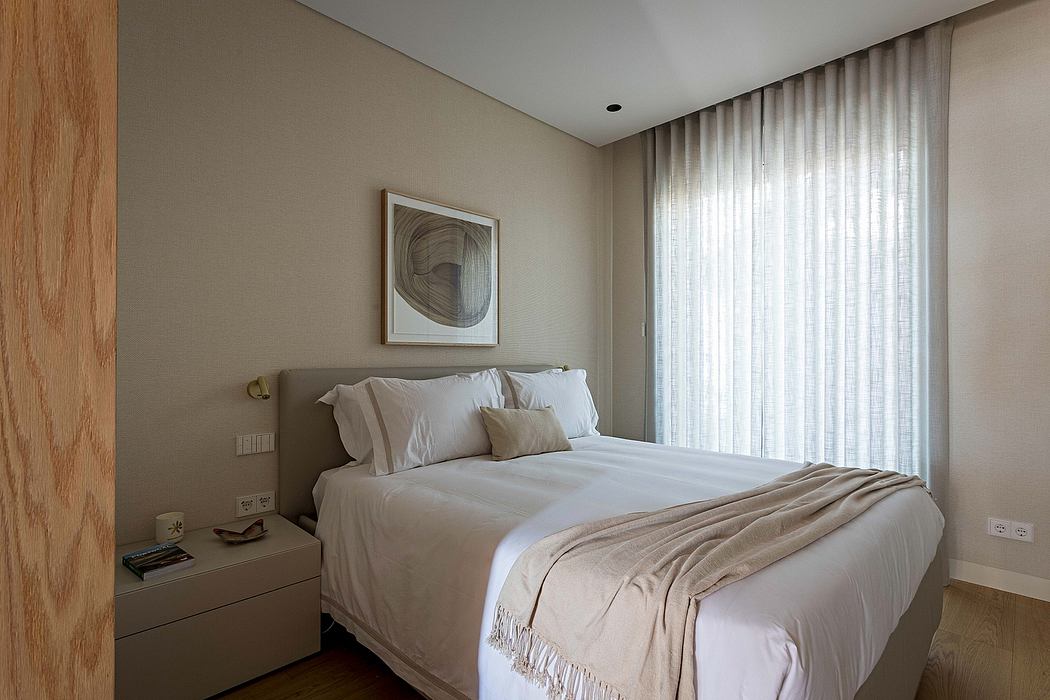 Modern bedroom with beige walls, white bed linen, and sheer curtains.