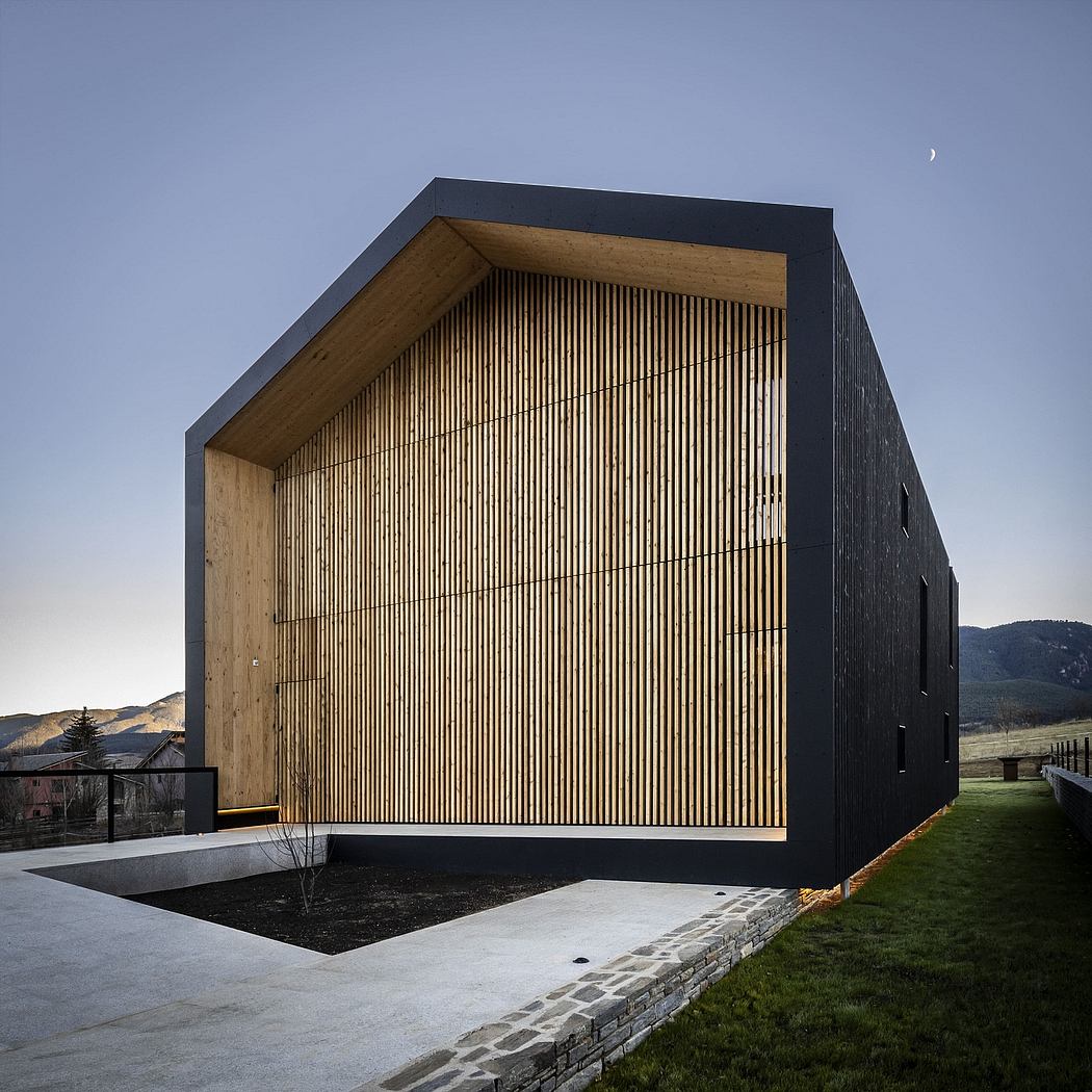 Modern architectural structure with wooden slat facade, black exterior, and grassy surroundings.