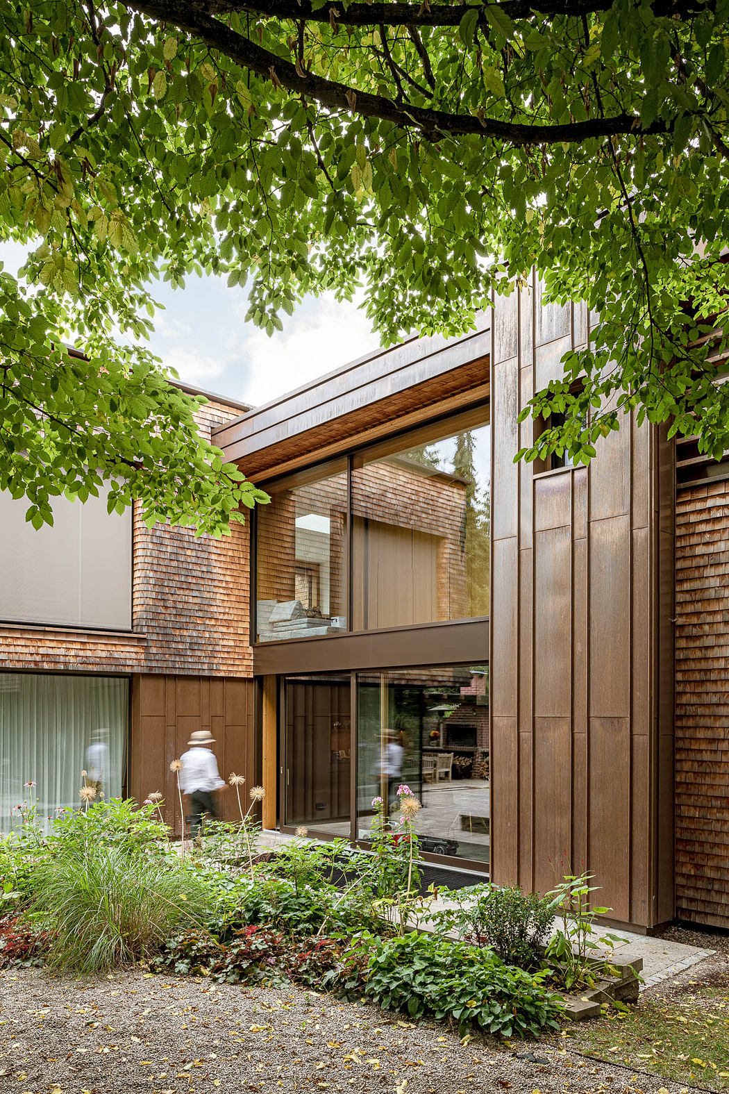 Modern two-story brick building with large windows surrounded by greenery.