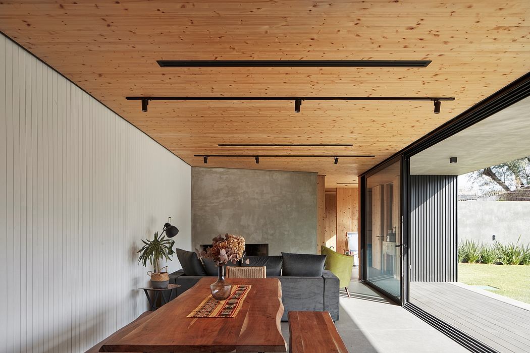 Contemporary dining space with wooden ceiling, large table, and glass sliding doors.