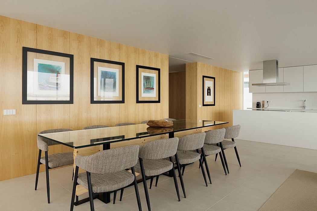 Modern, minimalist dining area with wooden walls, framed artwork, and glass-top table.