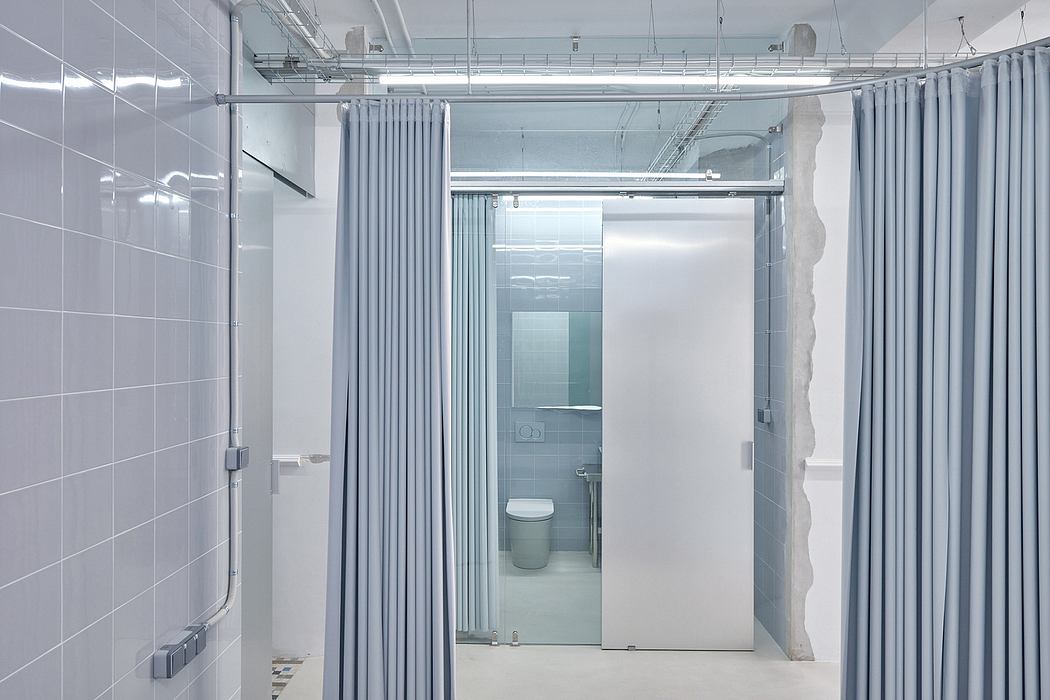 Modern industrial-style bathroom with glass walls, sliding door, and gray tiled surfaces.