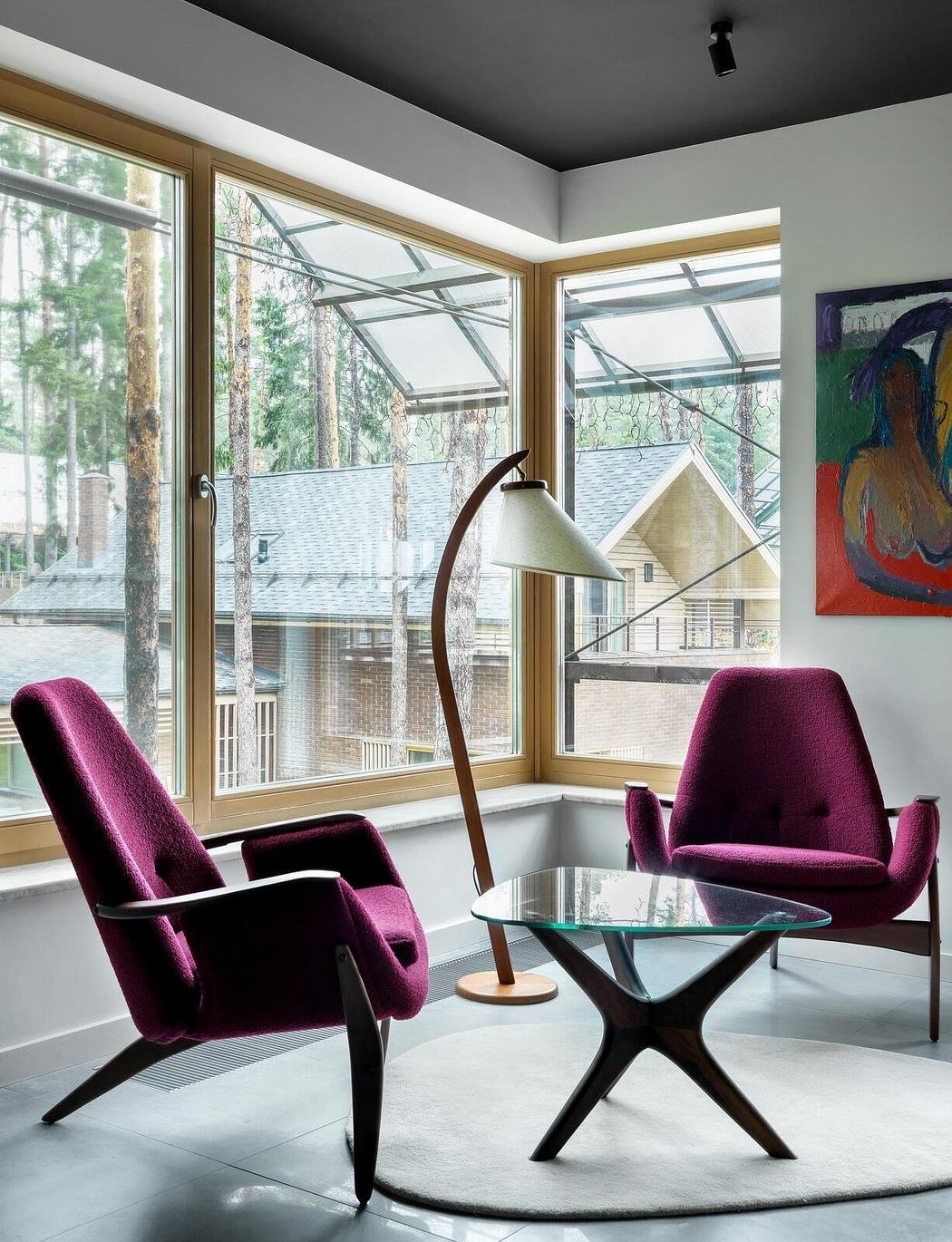 A cozy living room with floor-to-ceiling windows, plush purple chairs, and a minimalist glass coffee table.