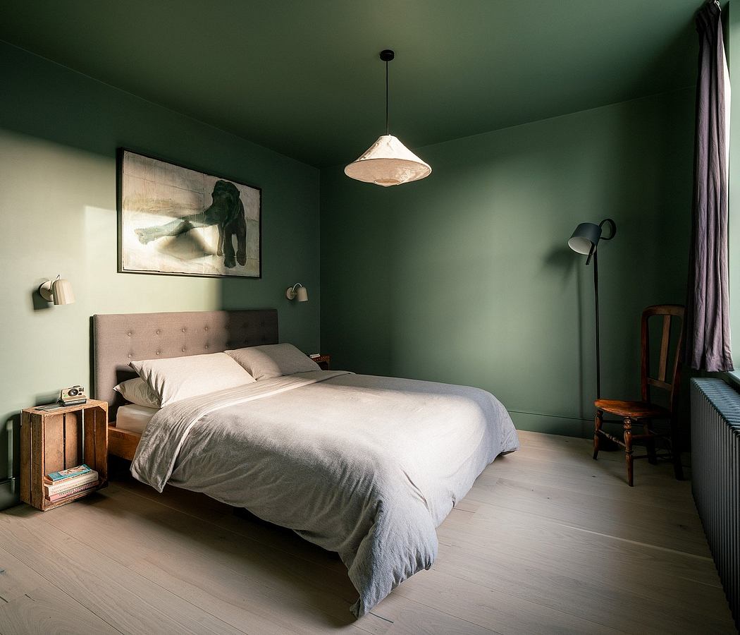 A minimalist bedroom with green walls, a large bed, and simple furniture.