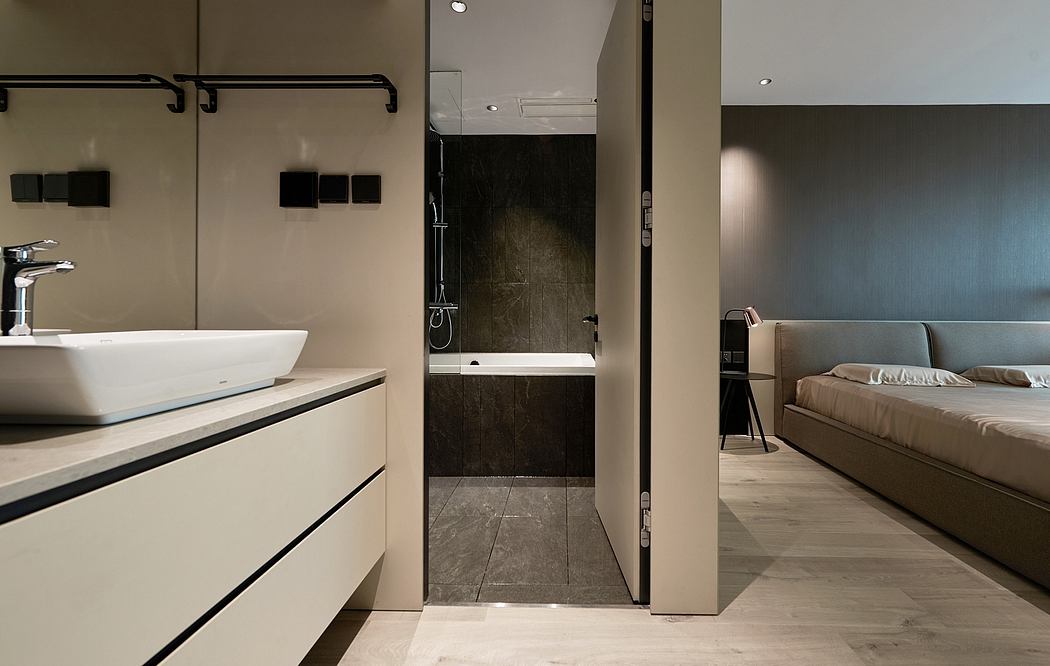 A modern bathroom with a sleek vanity, open shower, and adjoining bedroom area.