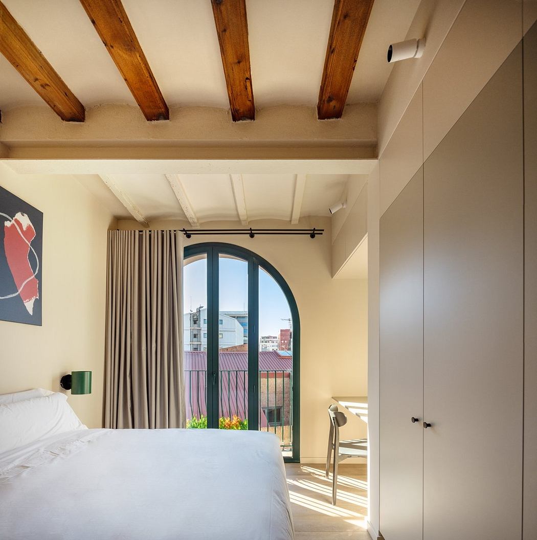 A cozy bedroom with wooden beamed ceilings, arched windows, and modern furnishings.