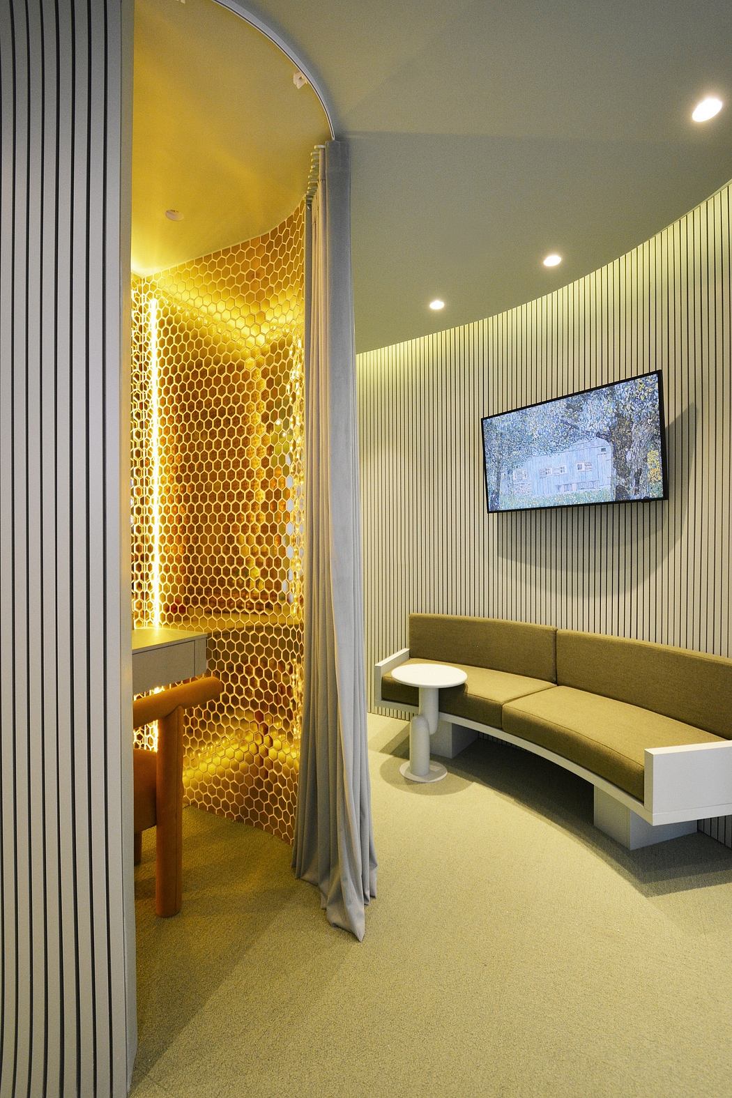 A modern interior design with a hexagonal yellow honeycomb feature wall, a TV display, and a curved sofa.