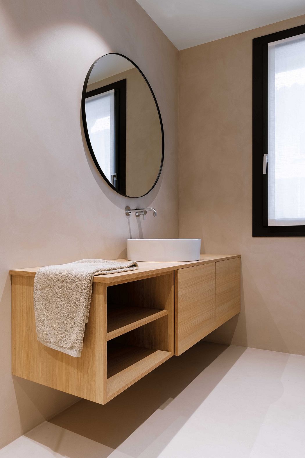 Contemporary bathroom with wooden vanity and round mirror.