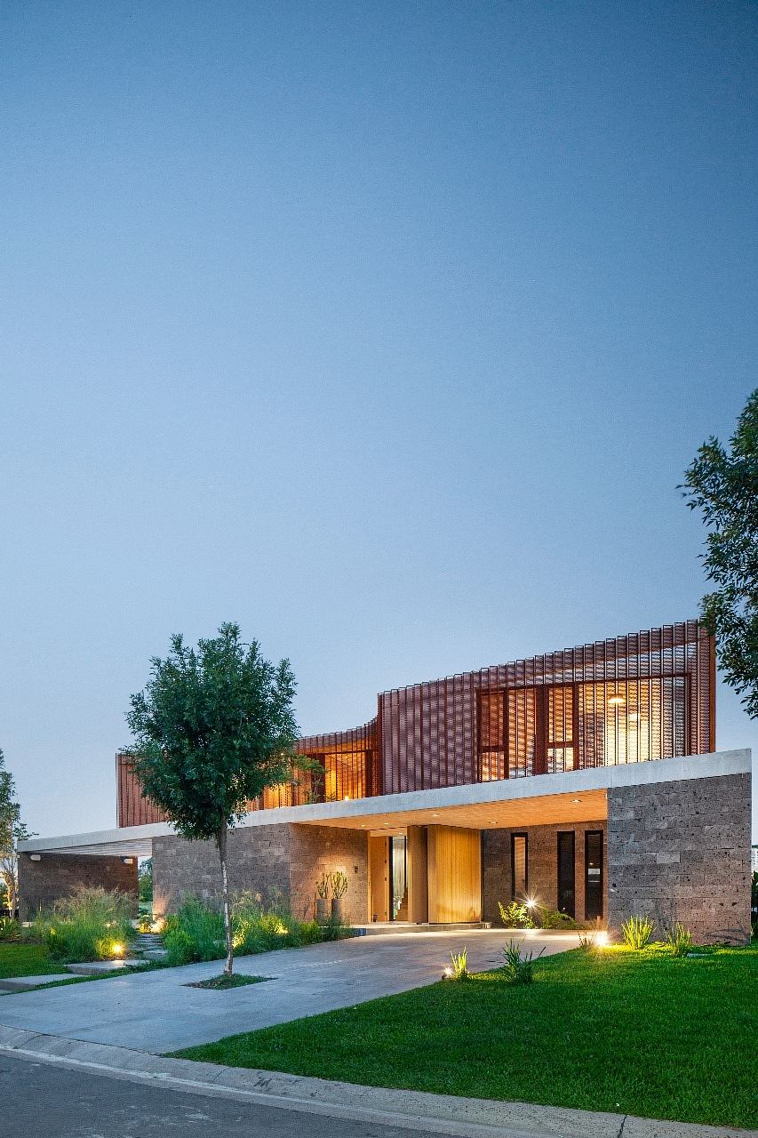 Modern house with illuminated facade and wooden slats at dusk.