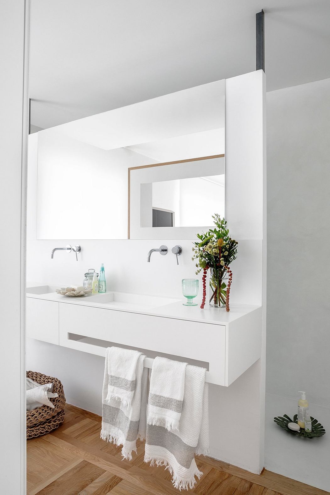 Minimalist bathroom with white vanity, dual sinks, and framed mirror with linear lighting.