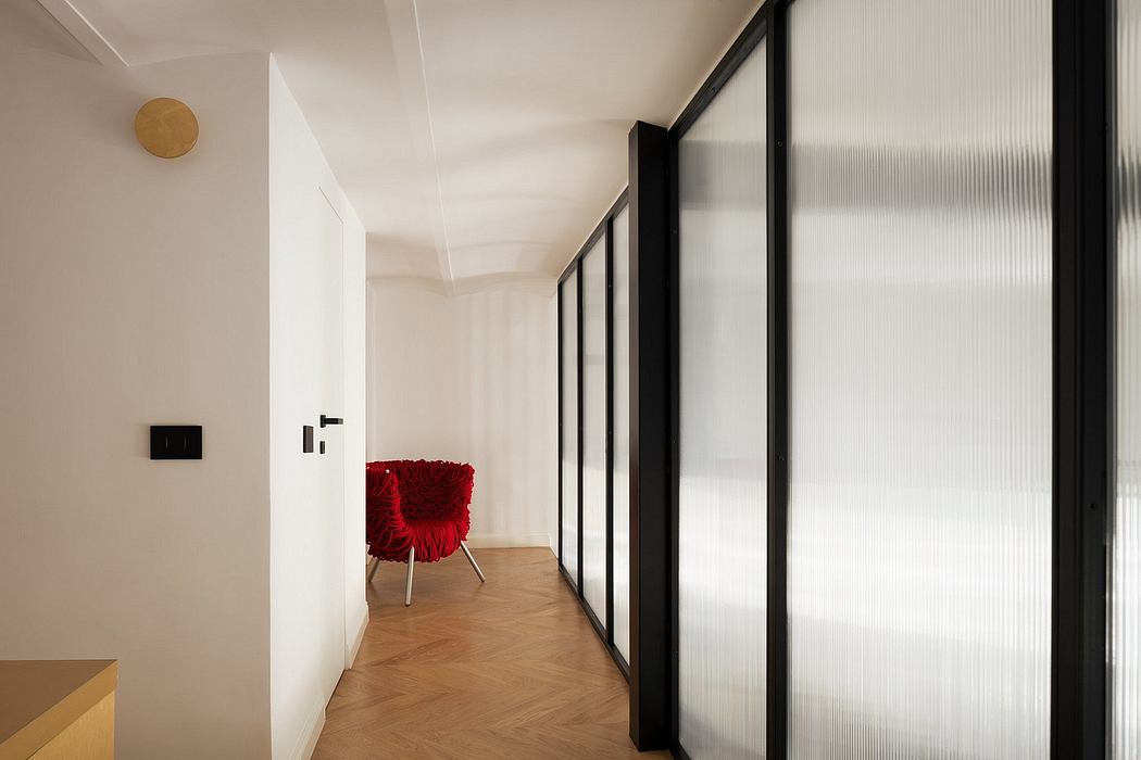 Minimalist hallway with translucent glass walls and a red chair.