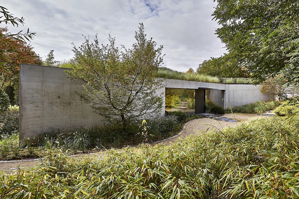 Modern concrete building amidst lush greenery with a curved pathway.