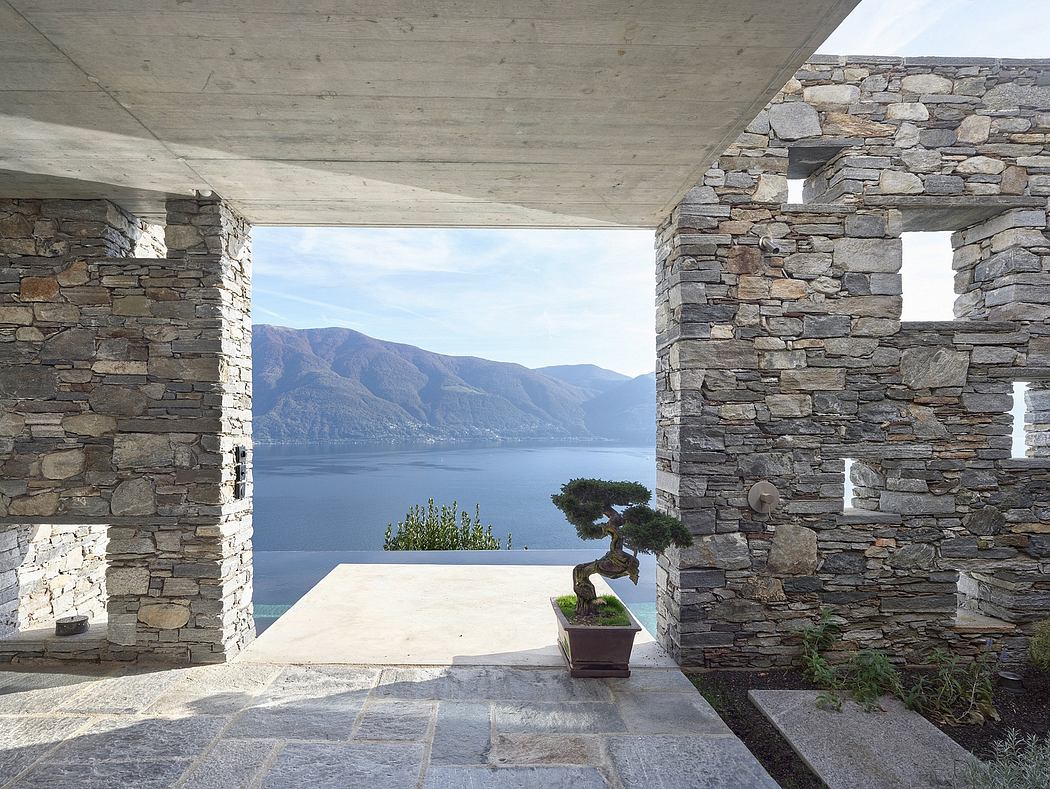 Stone building with open archway overlooking a lake.