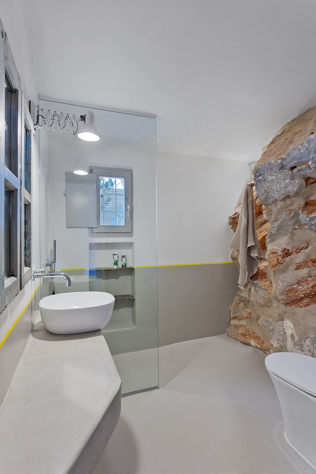 Modern bathroom with minimalist design, natural stone wall accent, and freestanding tub.