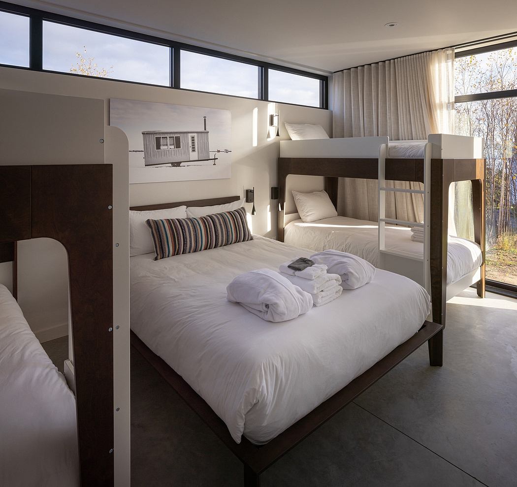 Modern bedroom with a double bed and bunk bed, large windows, and neutral tones