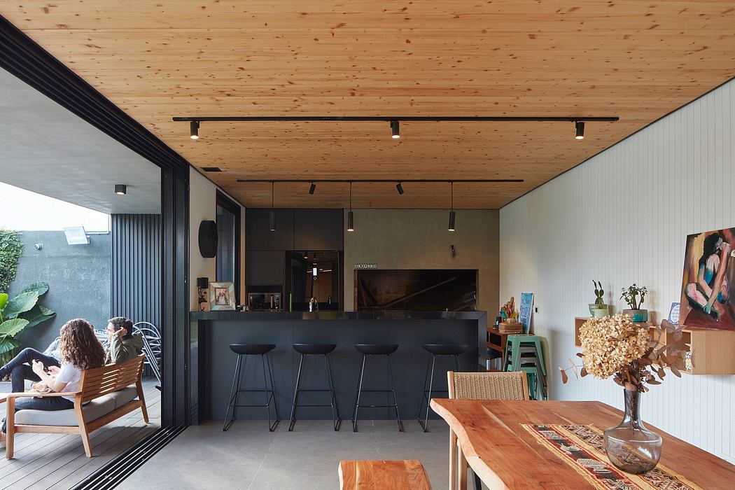 Contemporary open-plan living space with wooden ceiling and minimalist kitchen.