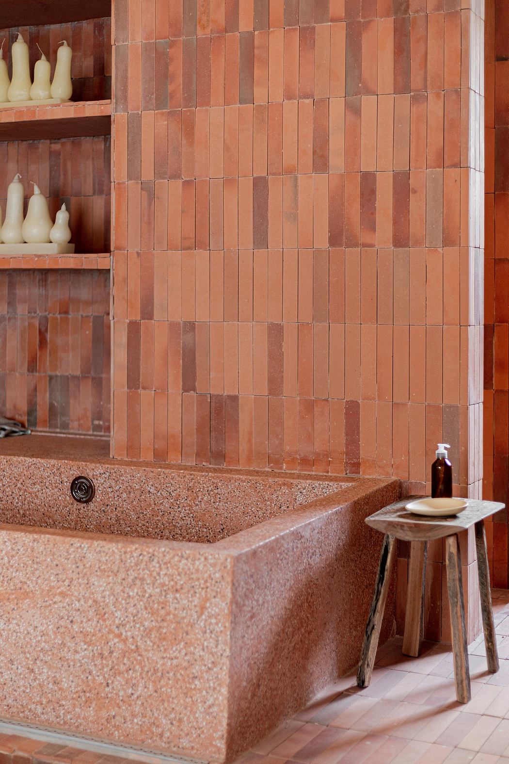 Terracotta tiled bathroom with a built-in sink and wooden stool.