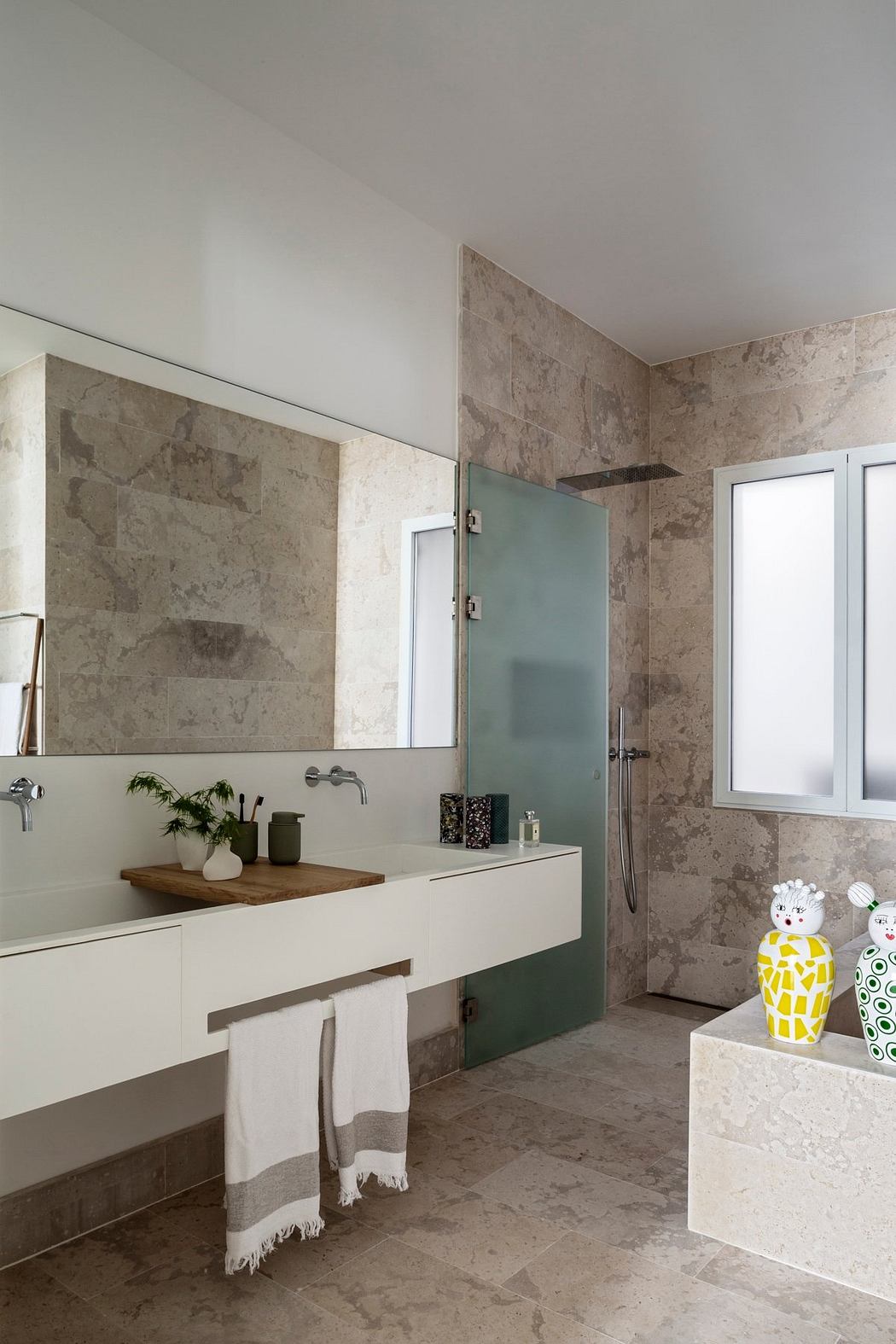 Modern bathroom with sleek white vanity, stone accent walls, and playful decor accents.