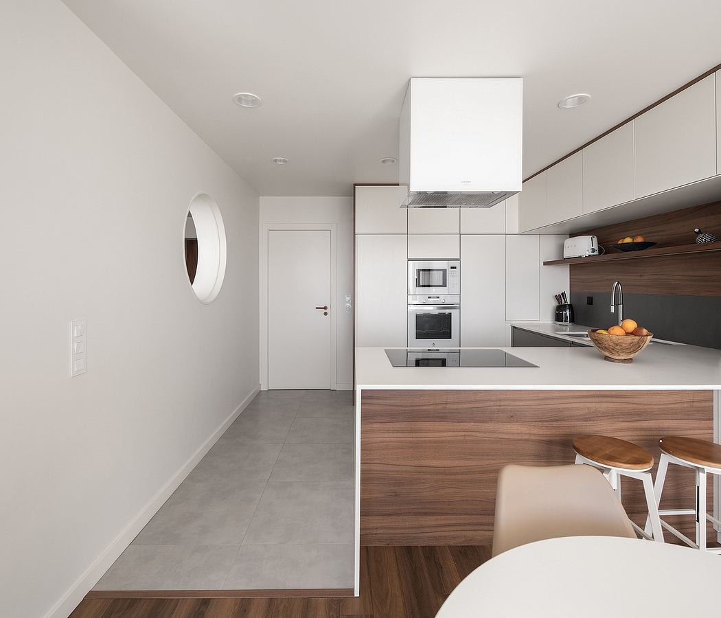 Sleek, modern kitchen with white cabinetry, wood accents, and a mirrored wall.
