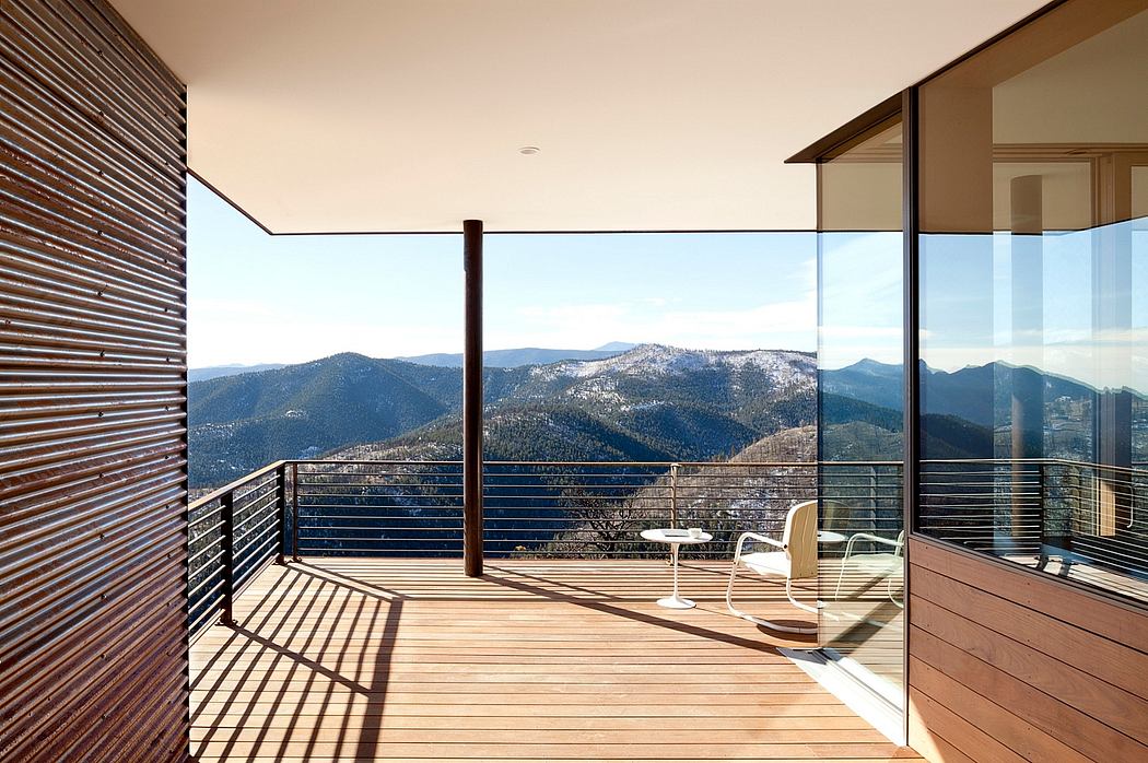 Contemporary balcony with mountain view, glass balustrade, and wooden floor.