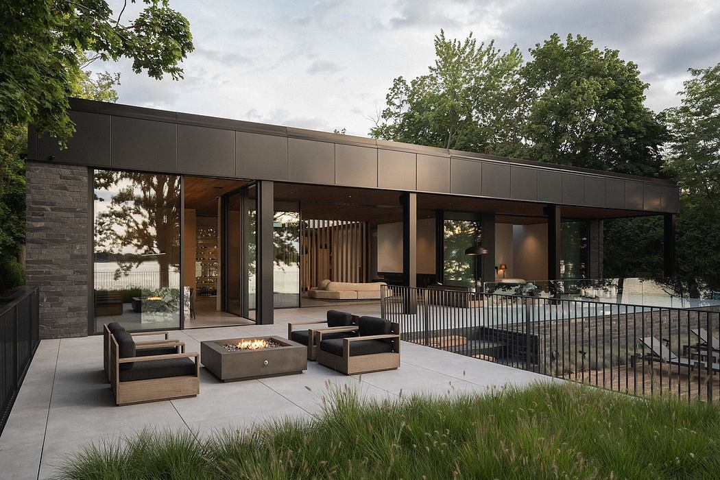 Modern outdoor living space with sleek black exterior, expansive glass walls, and cozy seating.