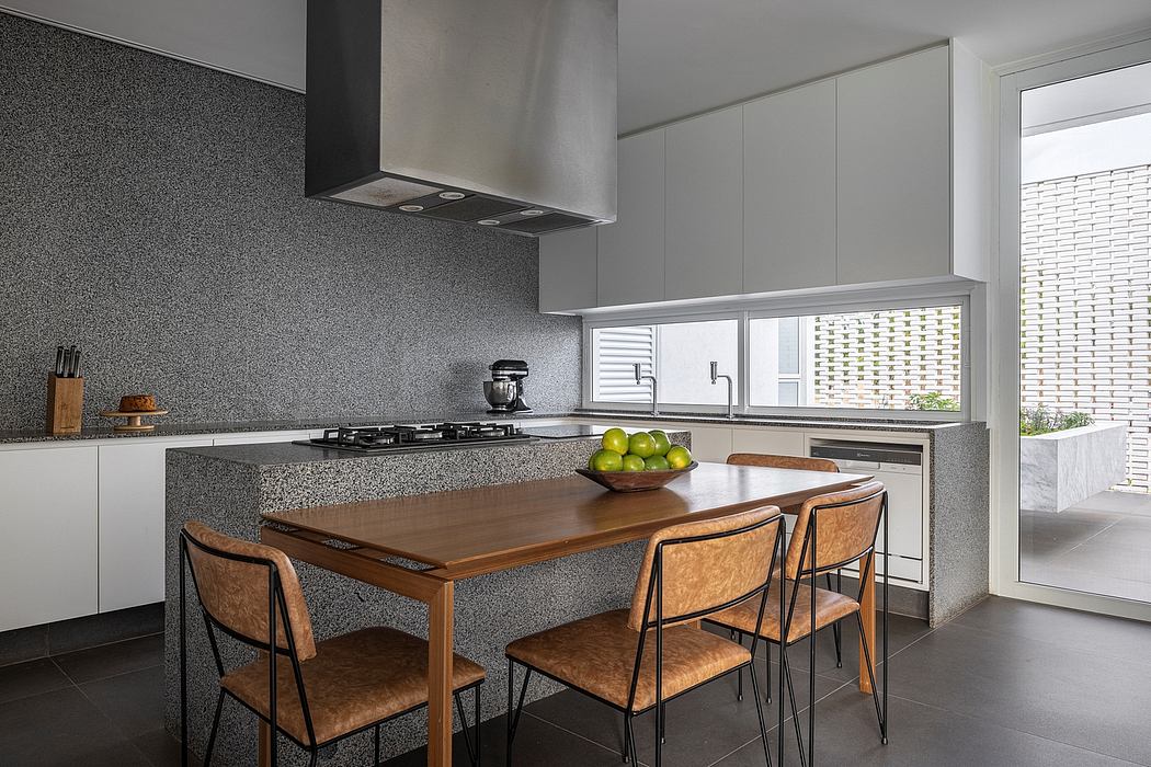 Modern kitchen with sleek gray cabinetry, wooden dining table, and marble countertops.